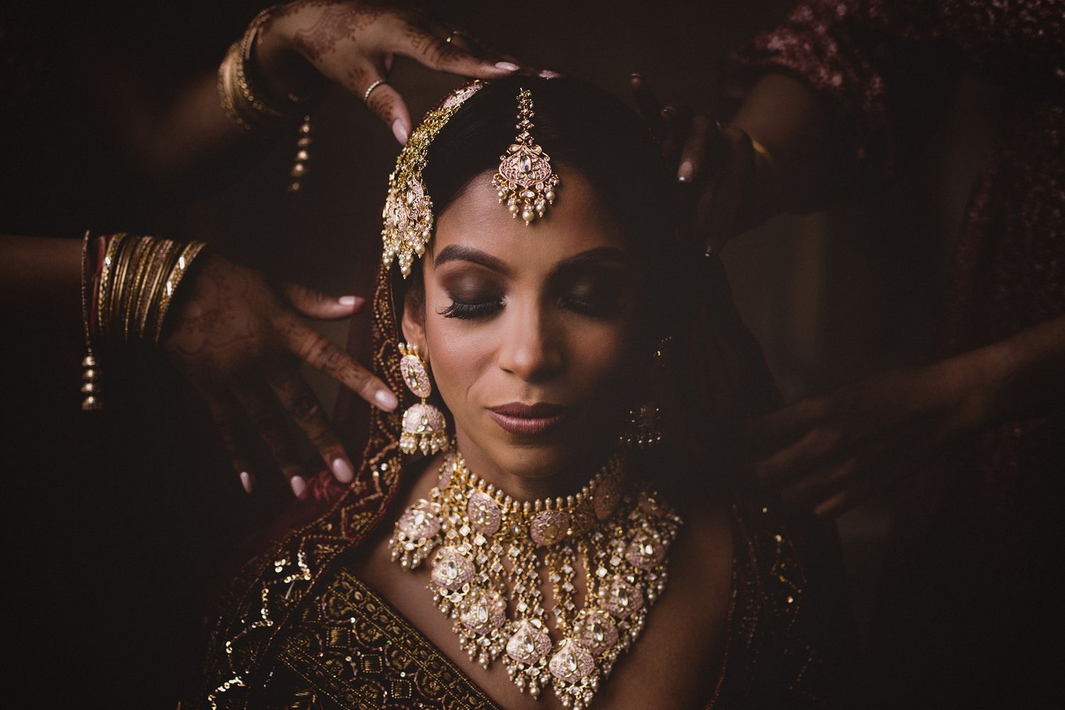 Traditional Indian bridal jewelry and accessories shown in dramatic lighting.