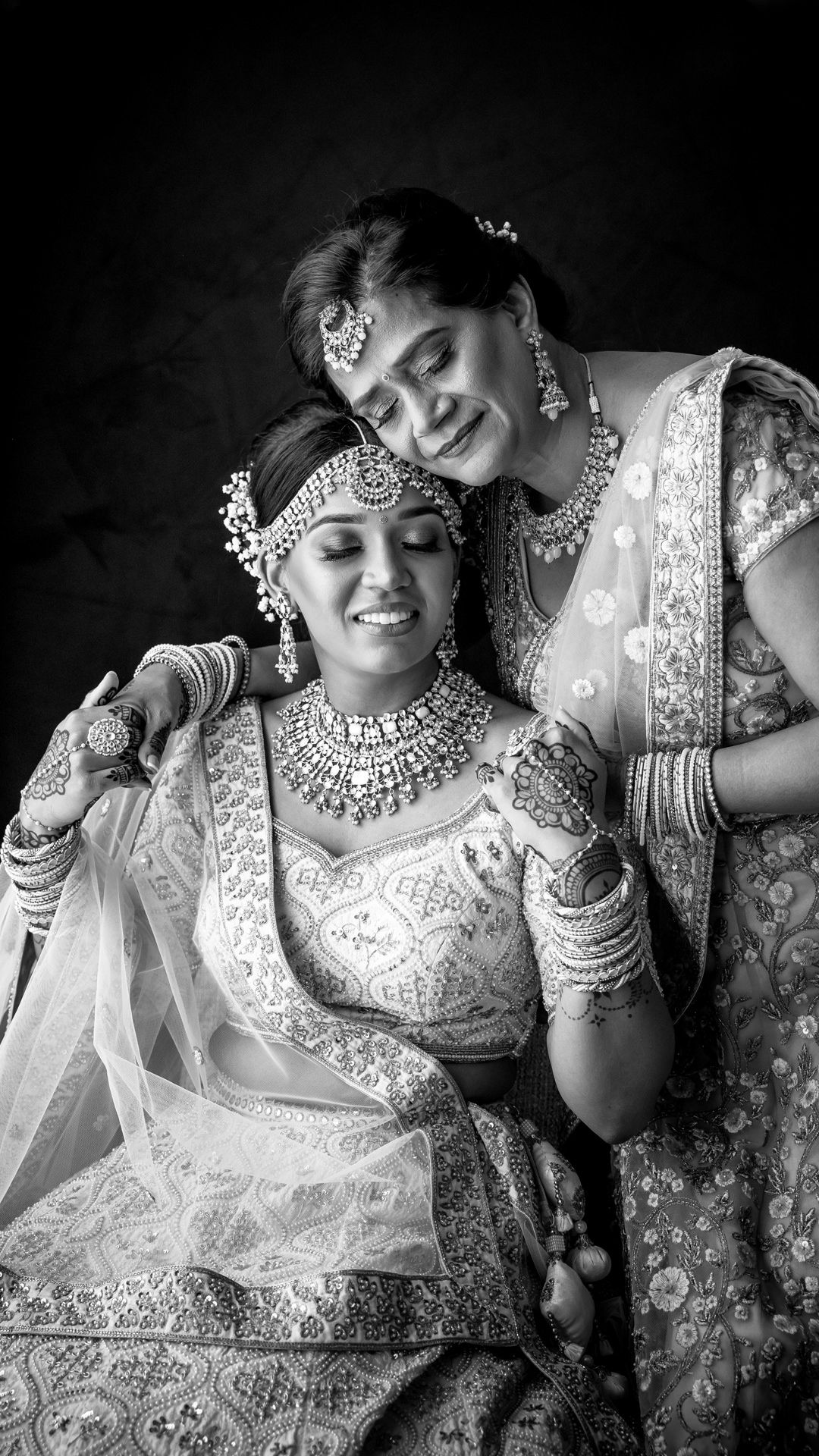 Black and white portrait of two women in traditional Indian wedding attire and jewelry.