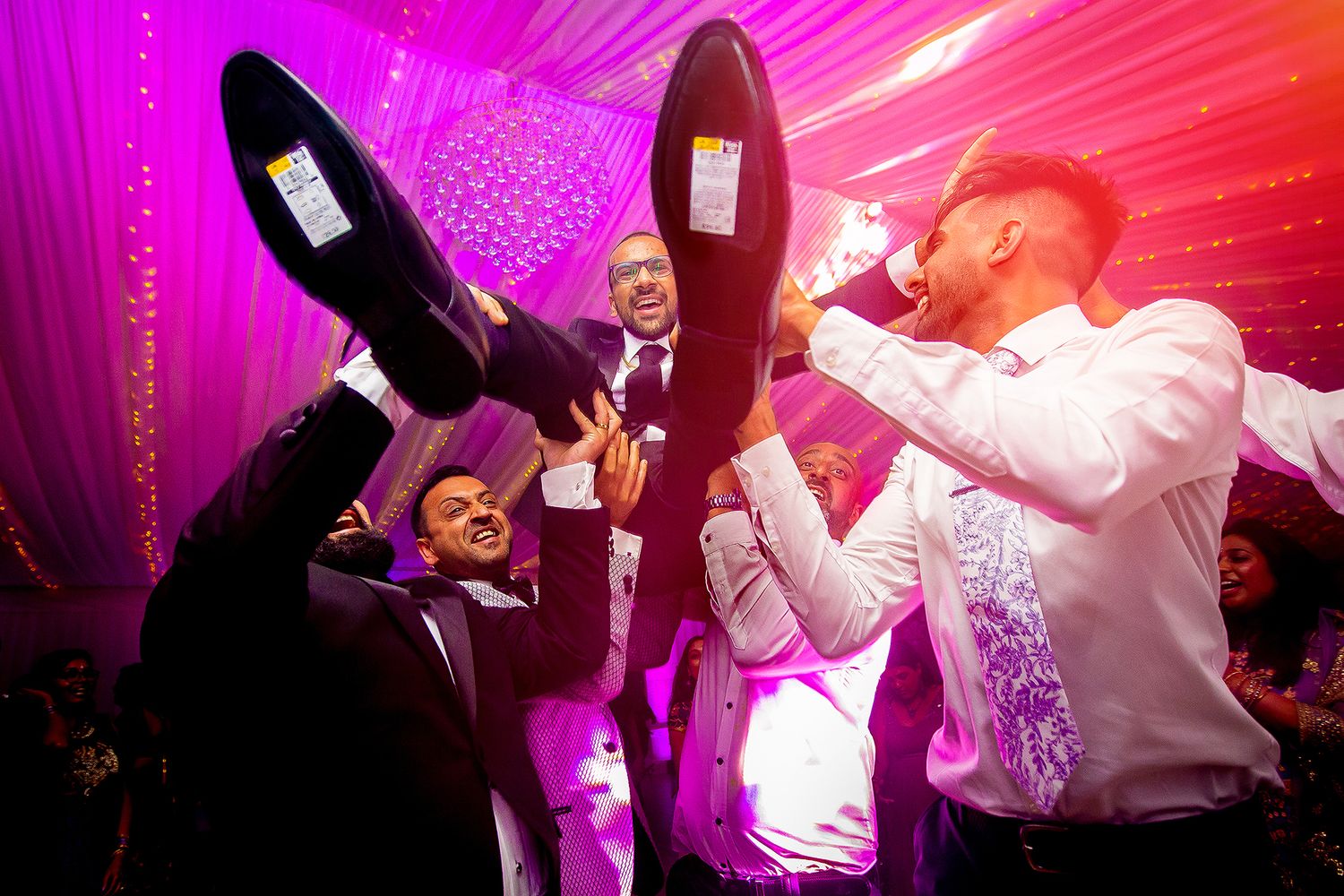 Wedding reception dance party with vibrant pink lighting and energetic atmosphere.