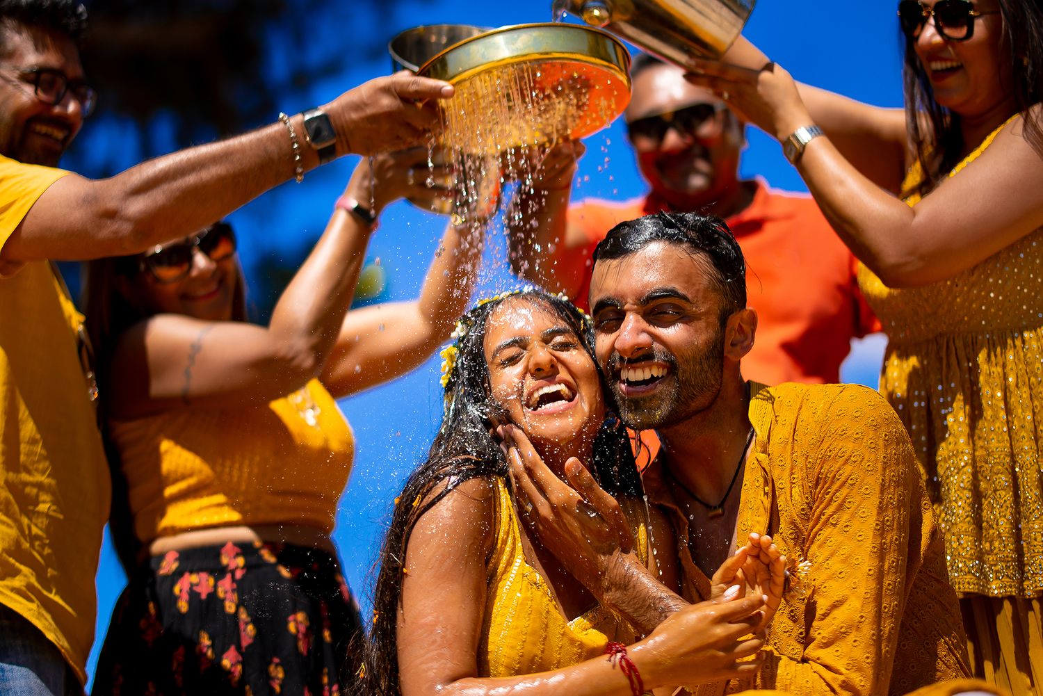 Joyful celebration with yellow-clad dancers performing traditional Indian dance moves at a wedding event.