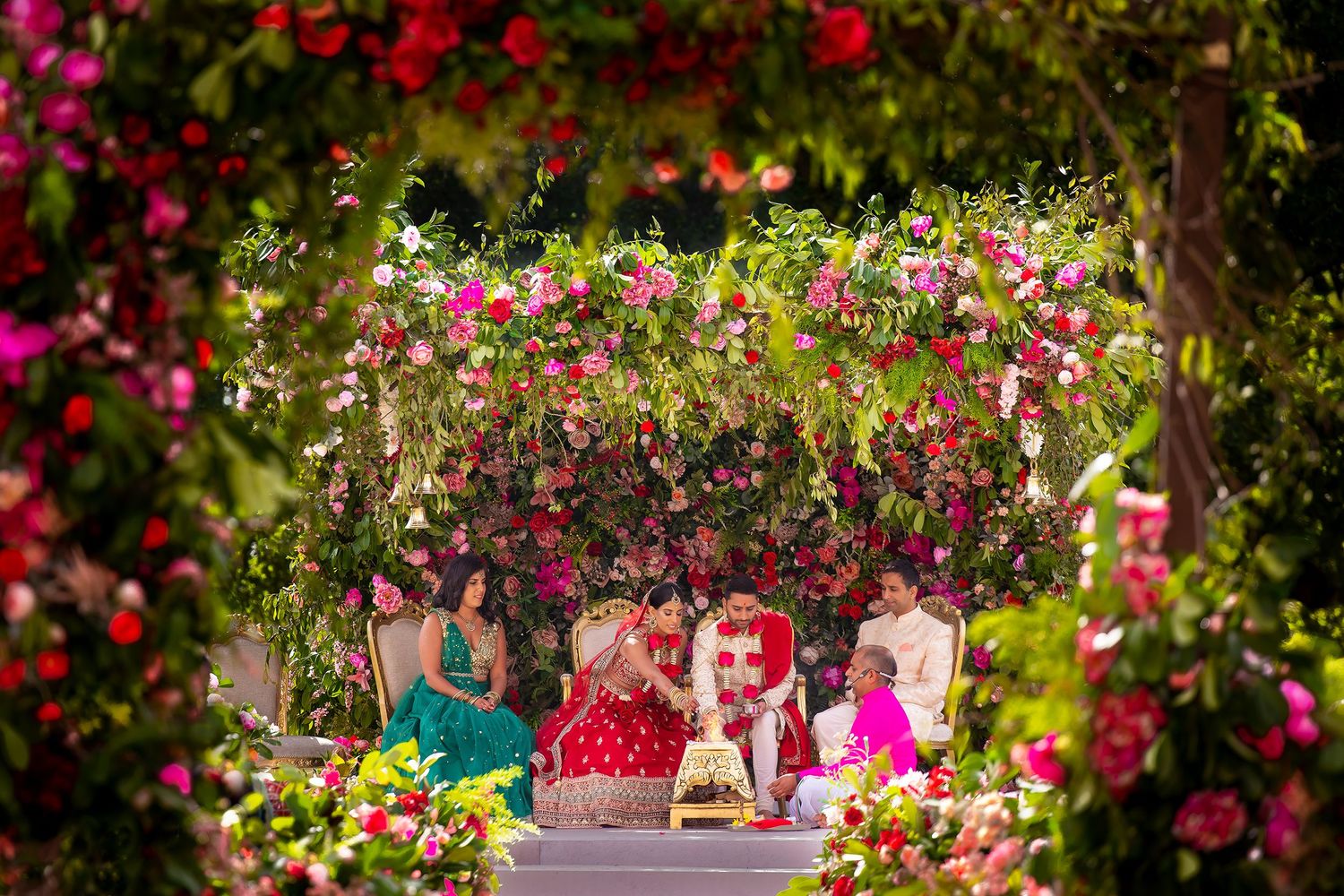People enjoy a picturesque garden setting surrounded by vibrant pink flowers and lush greenery.