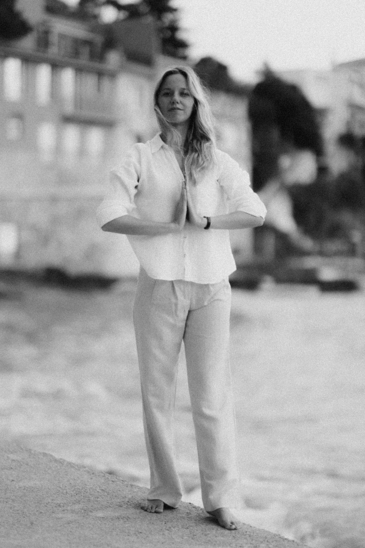 Black and white photo series of person in all-white outfit moving on beach.