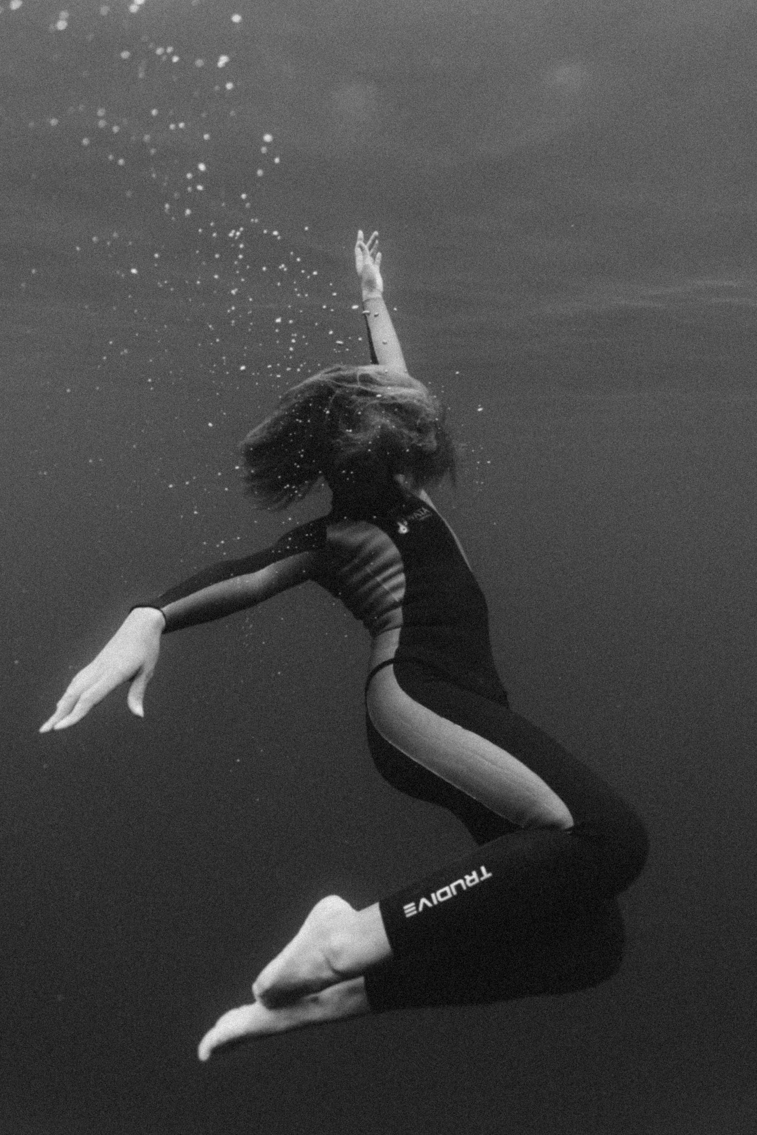 A graceful underwater dancer performs a dynamic sequence of movements in black and white photography.