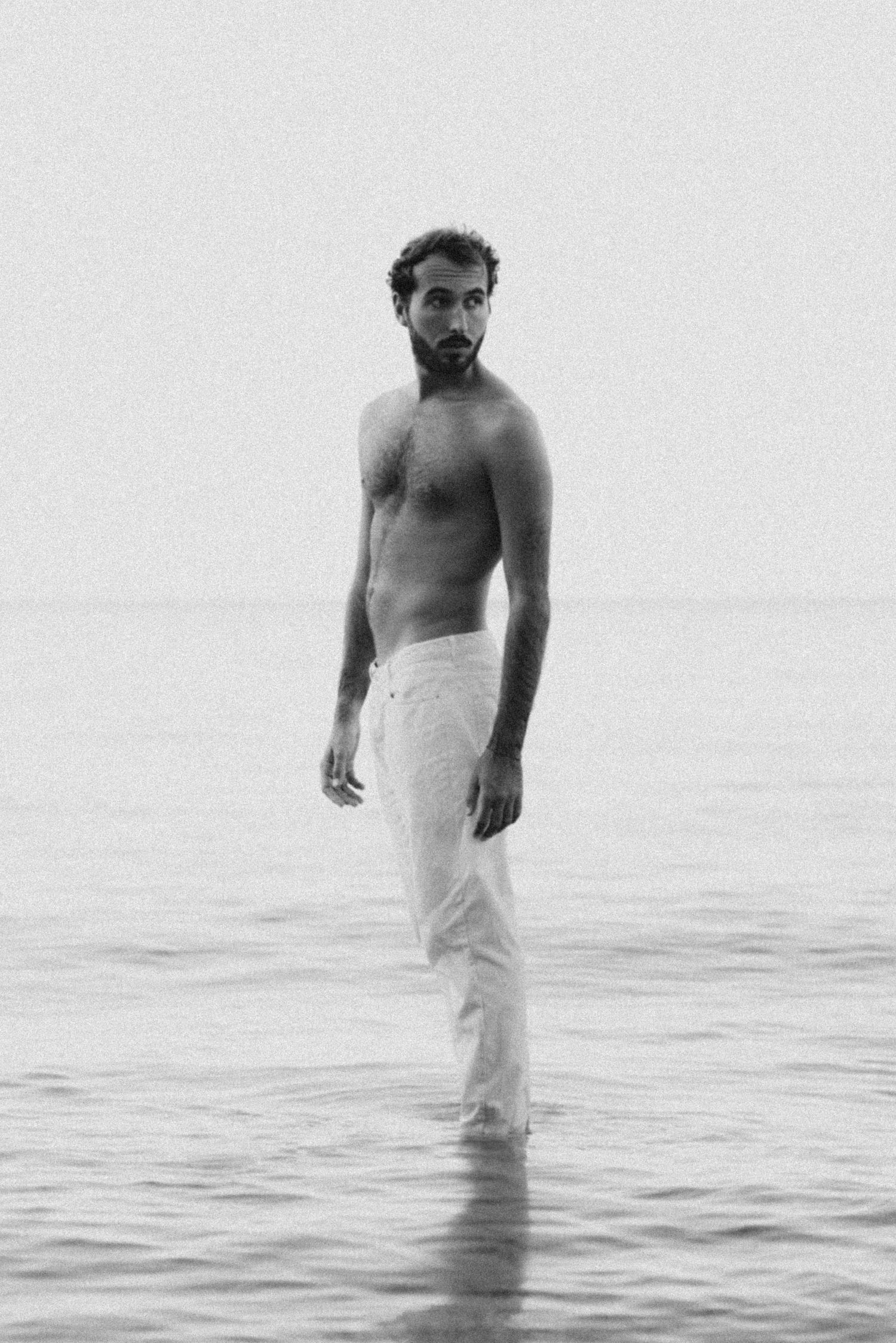 Black and white photo sequence of someone wading through tranquil ocean waters.
