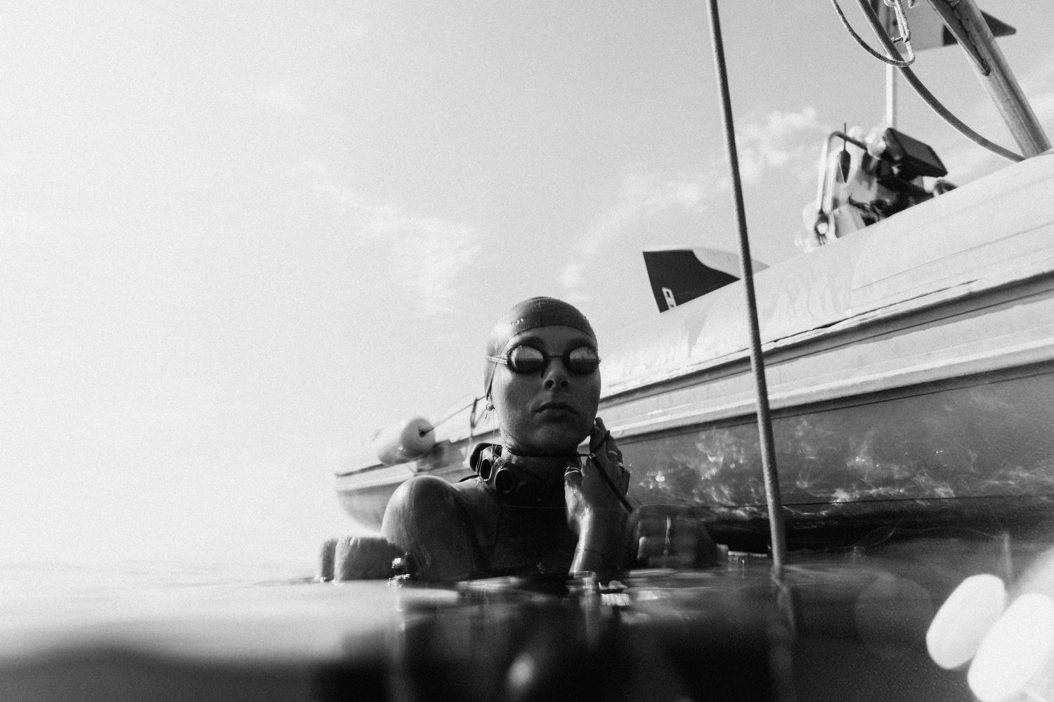 Underwater view of scuba diver with equipment against bright surface.