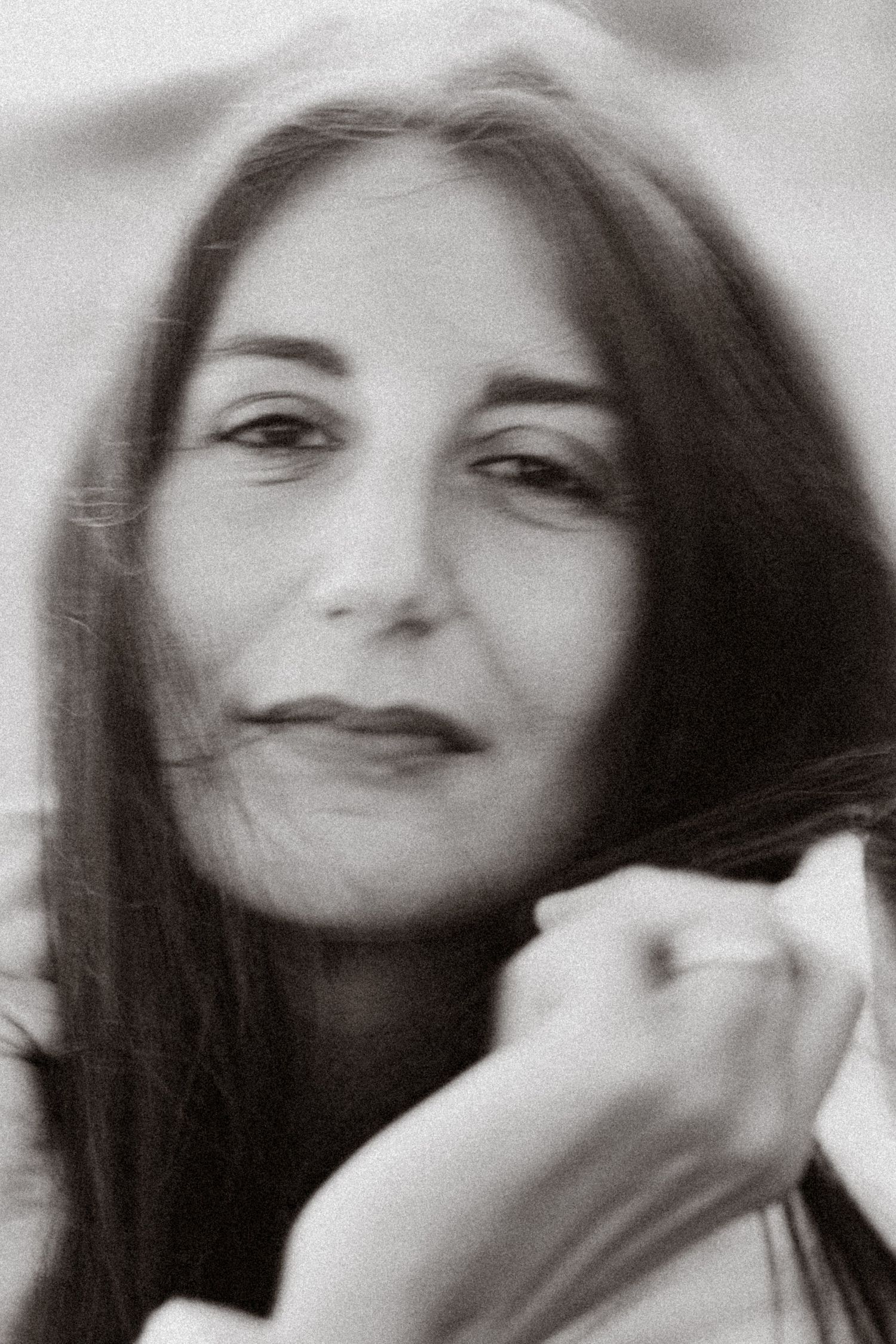 Black and white portrait of a woman with long dark hair, gazing at the camera with a soft, contemplative expression.
