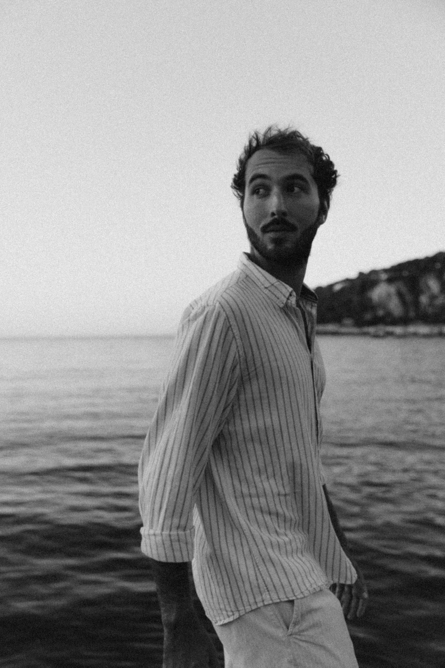 Black and white portraits showing different poses in striped shirt against ocean backdrop.