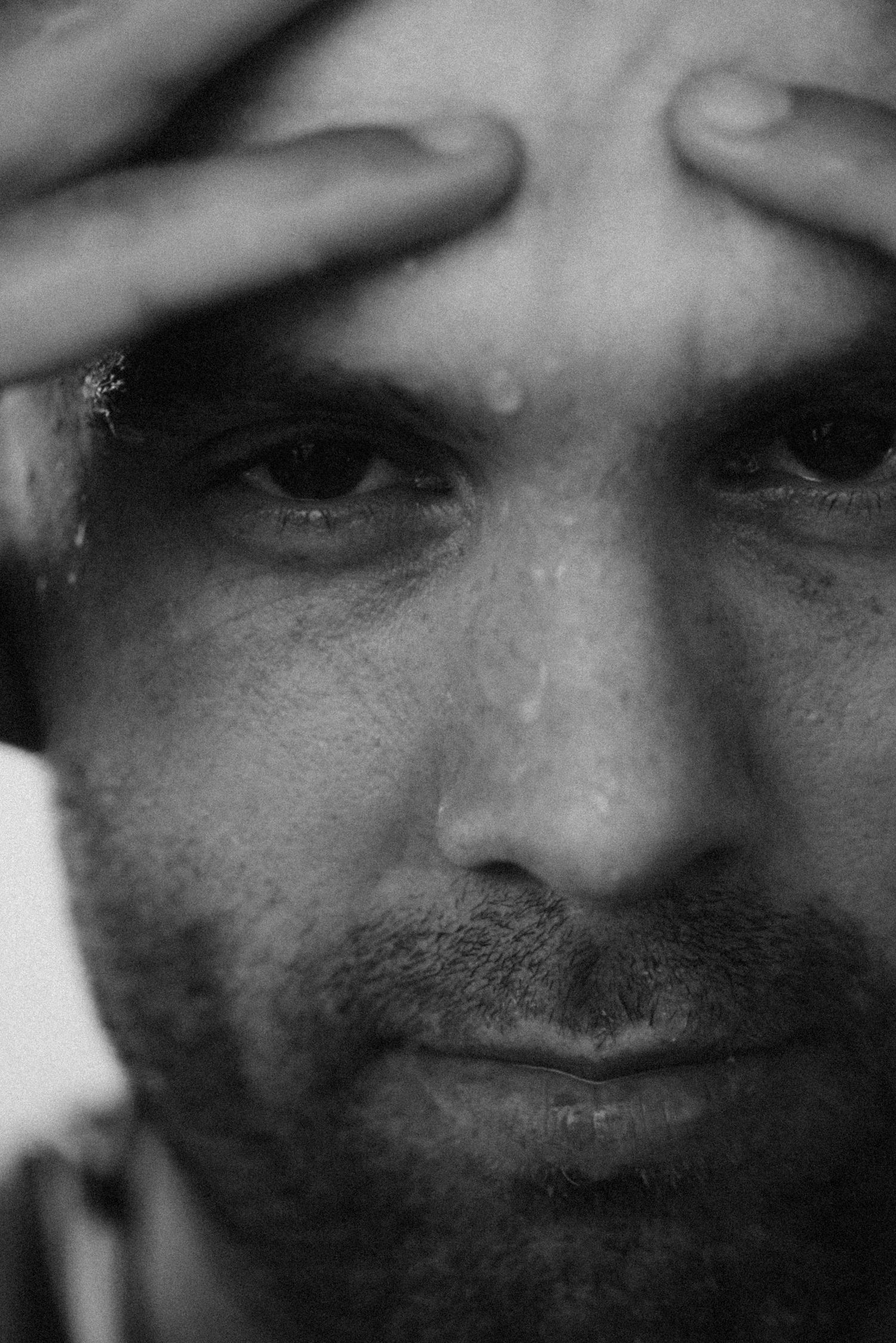 Extreme close-up black and white portrait showing facial features in dramatic lighting.