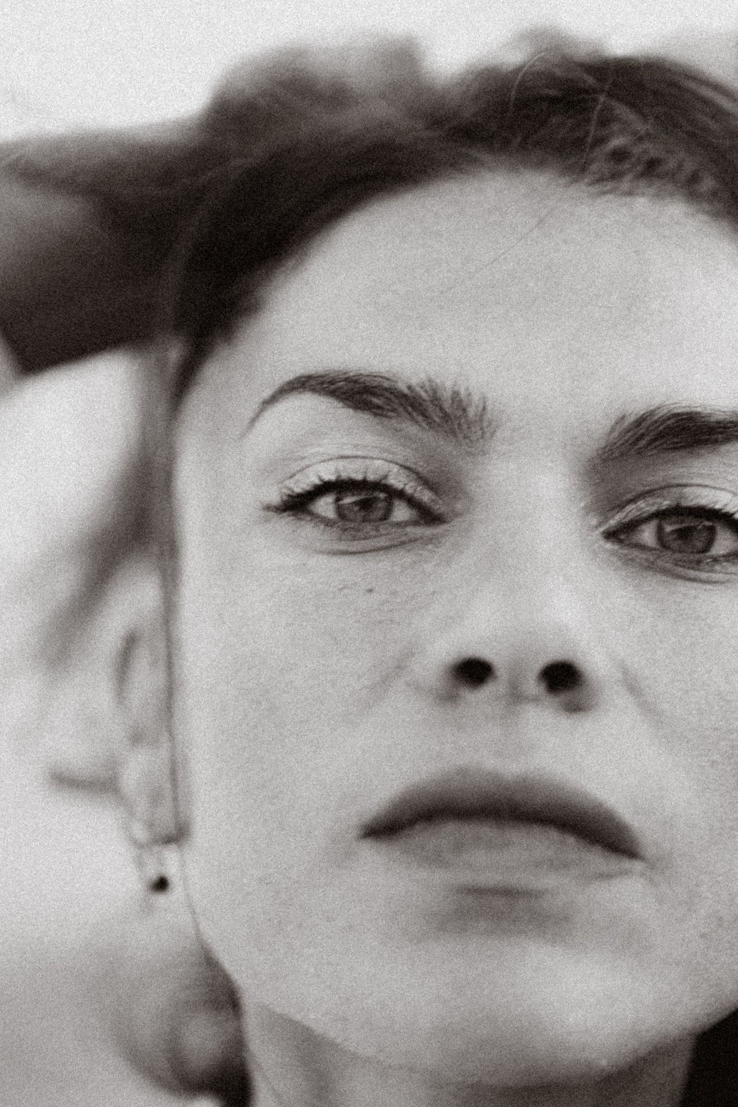 Black and white close-up portrait of a woman with dark hair and expressive eyes gazing into the distance.