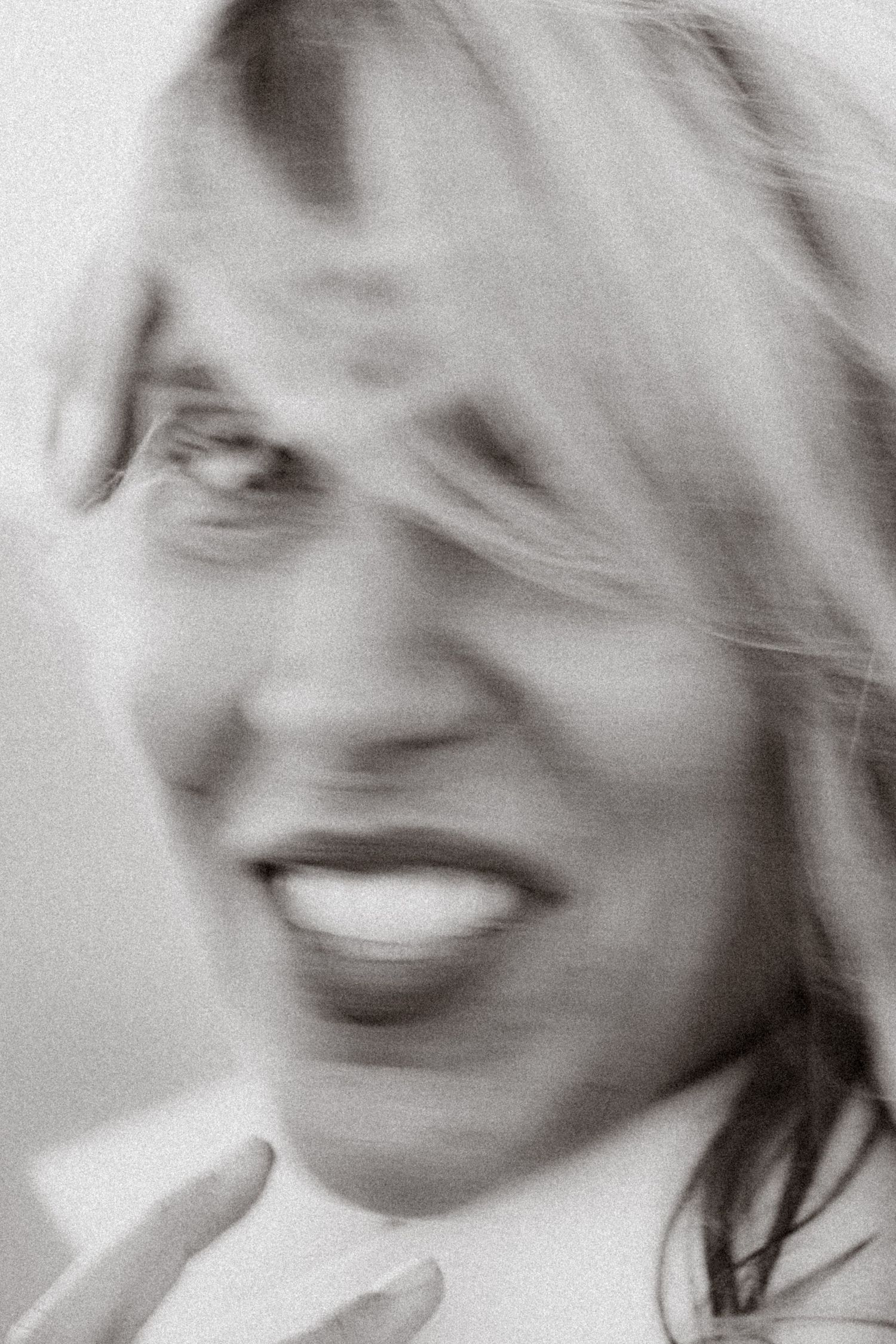 Blurry black and white portrait of a smiling blonde woman with motion blur effect.