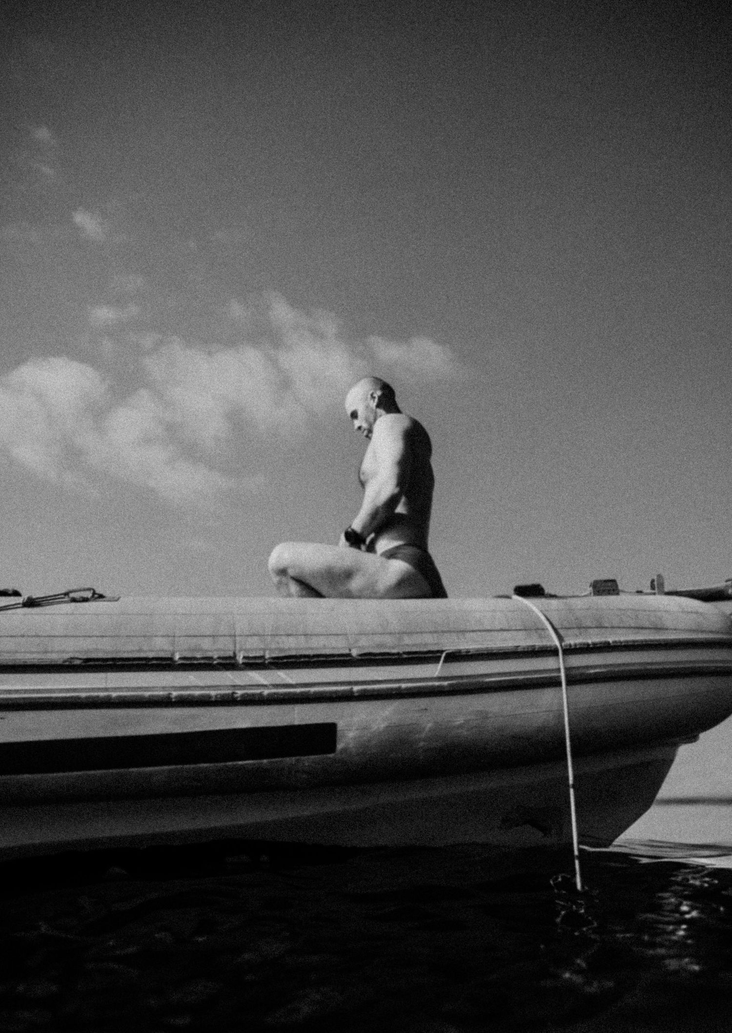 Black and white photo series of a person lying on a dock over water against cloudy sky.