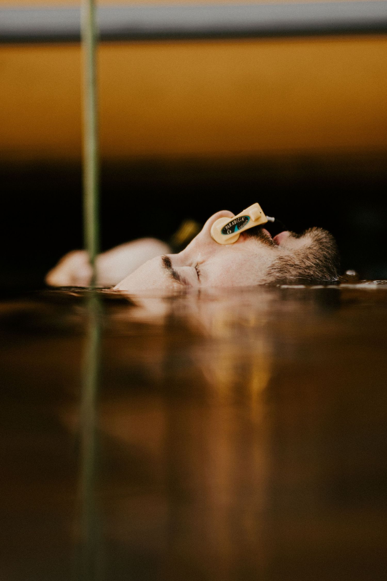 Atmospheric close-up profile shot partially submerged in water with warm toned lighting.