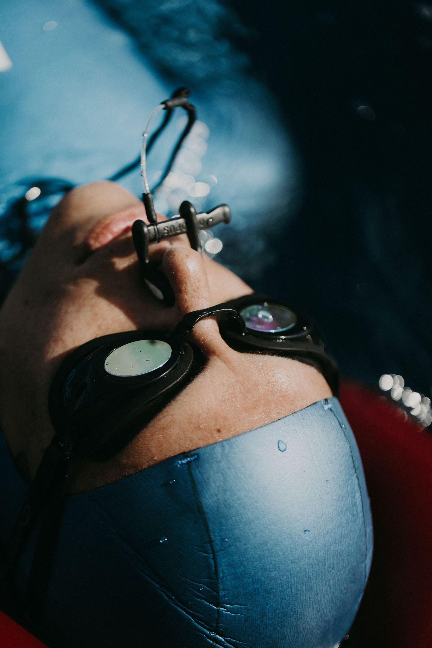 Close-up of a swimmer wearing goggles and a swim cap, floating in a pool with a breathing device.