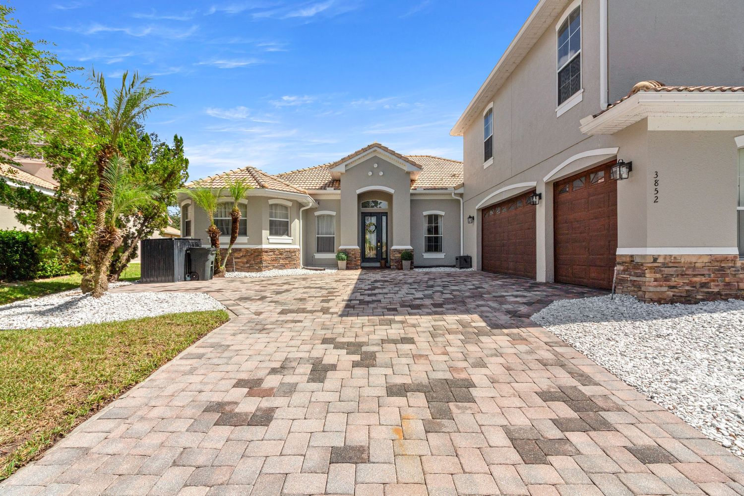 Impressive Davenport Florida home exterior featuring Mediterranean architecture, paver driveway, tile roof, and desert landscaping.