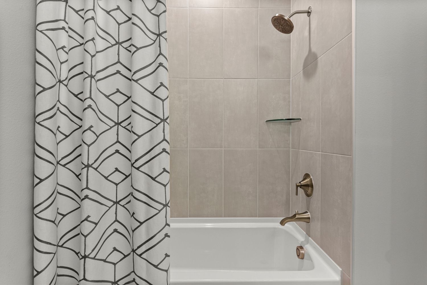 Contemporary bathroom photography in Groveland Florida showcasing geometric tile accent wall, bathtub alcove, and neutral color palette.