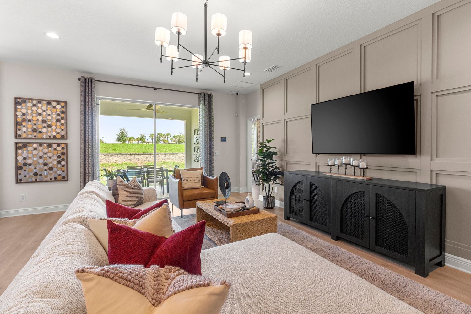 Elegant Davenport Florida living room featuring red accent chairs, mounted TV, chandelier, and warm neutral tones. Professional Polk County