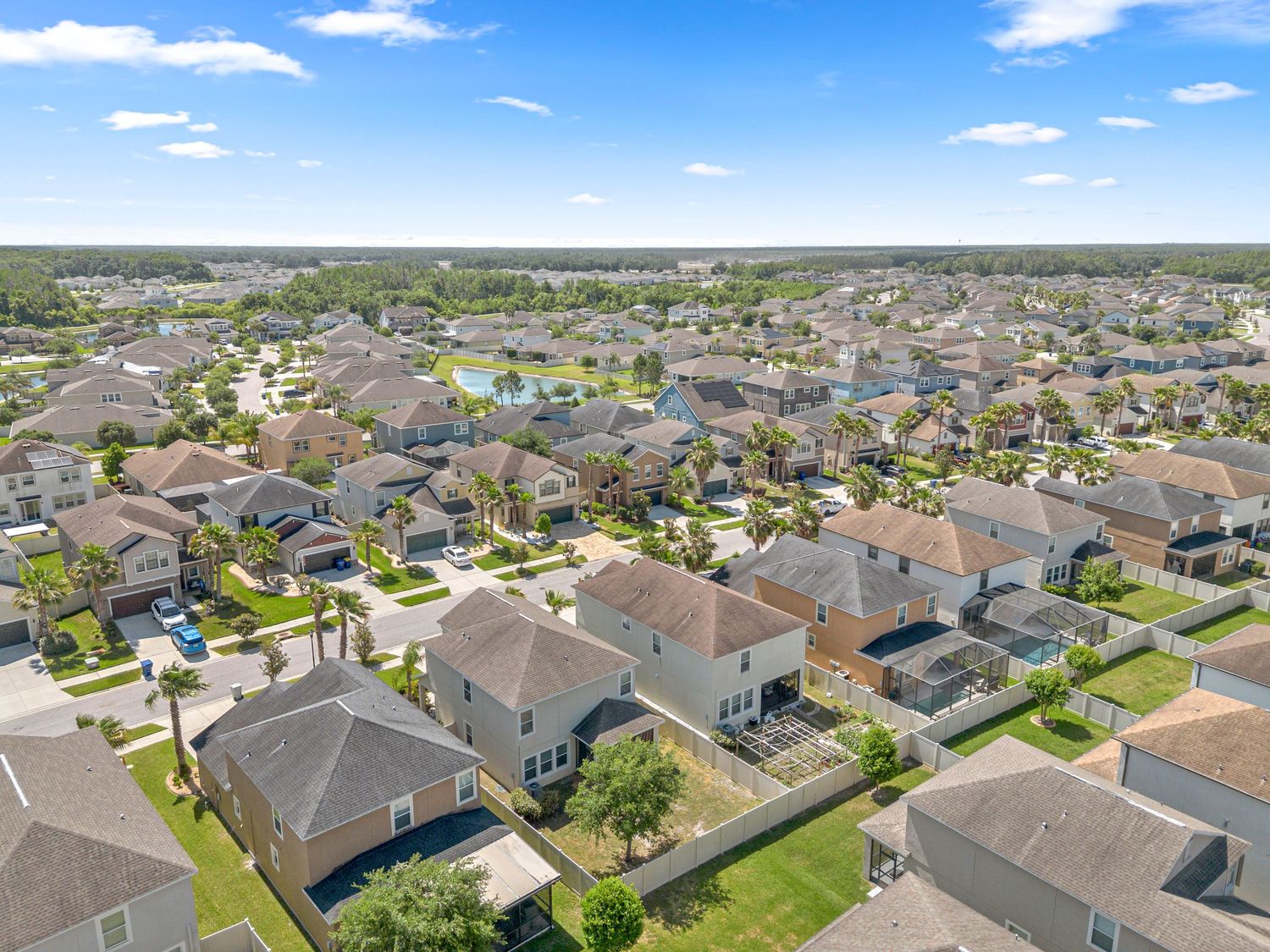 Aerial drone view of suburban neighborhood with homes and greenery under blue sky – Central Florida real estate photography / media