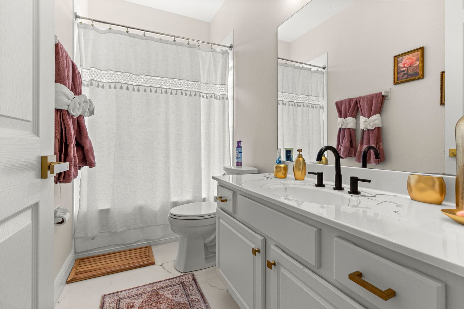 Luxurious Kissimmee Florida master bathroom featuring double vanity sinks, gray cabinetry, walk-in shower, and burgundy towel accents.