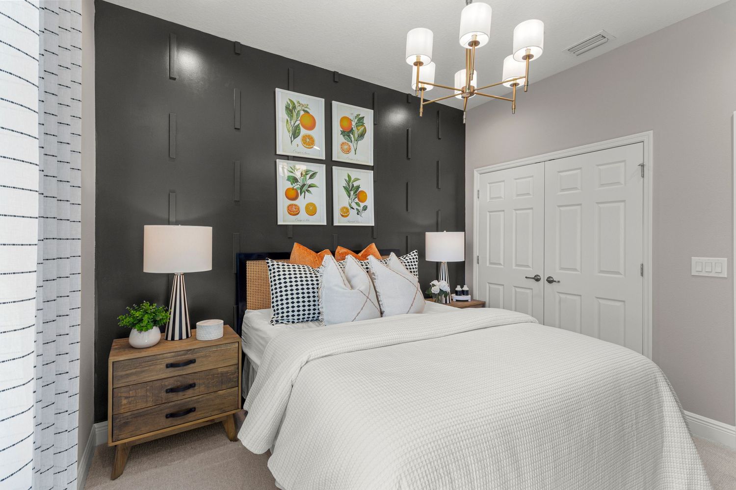 Sophisticated Clermont Florida master bedroom with gray accent wall, white bedding, gallery wall artwork, and modern chandelier. Real estate