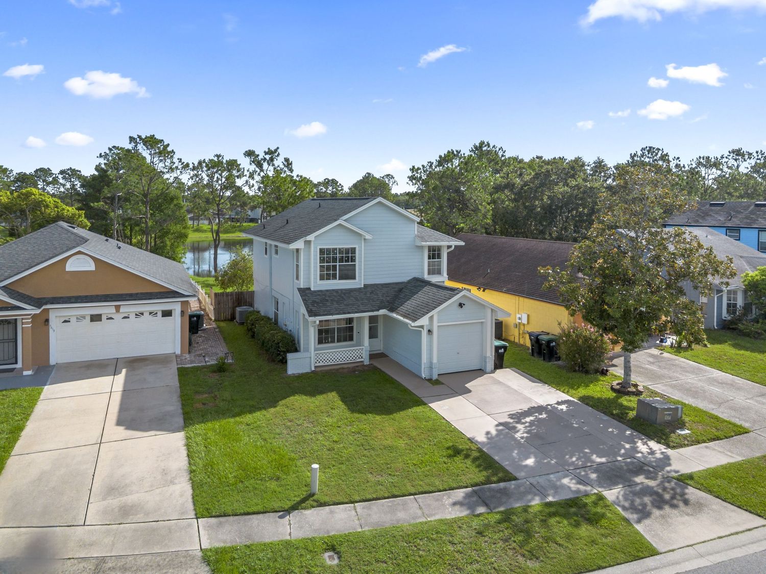 Front aerial view of a two-story Central Florida house featuring a spacious driveway, attached garage, and well-kept lawn.