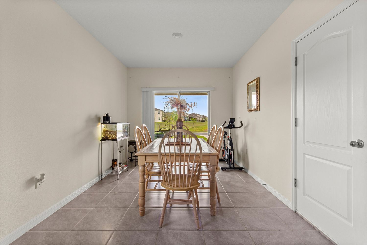 Spacious dining room with clean layout, tile flooring, and natural light in Florida home