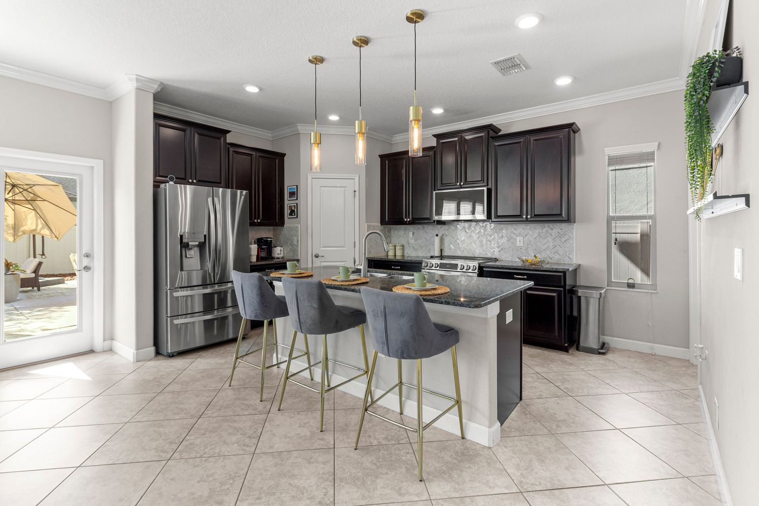 Modern kitchen with island seating, pendant lighting, and stainless appliances – Central Florida real estate photography