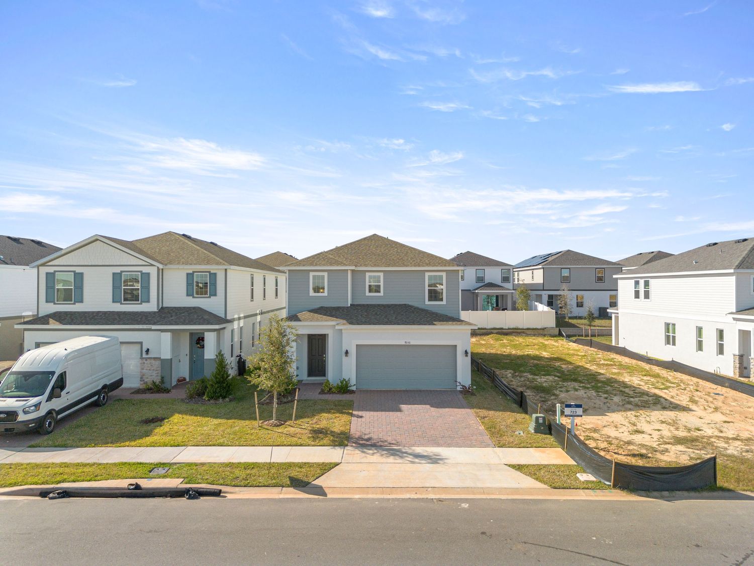 Aerial front view of suburban single-family home with driveway and neighboring houses, captured with professional real estate drone media.