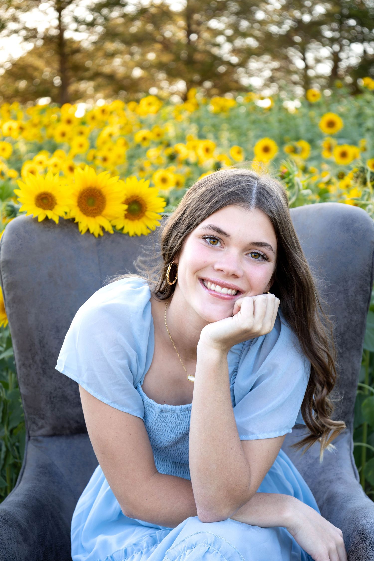 This senior is sitting in a chair in the middle of the a sunflower field in Marshfield MO