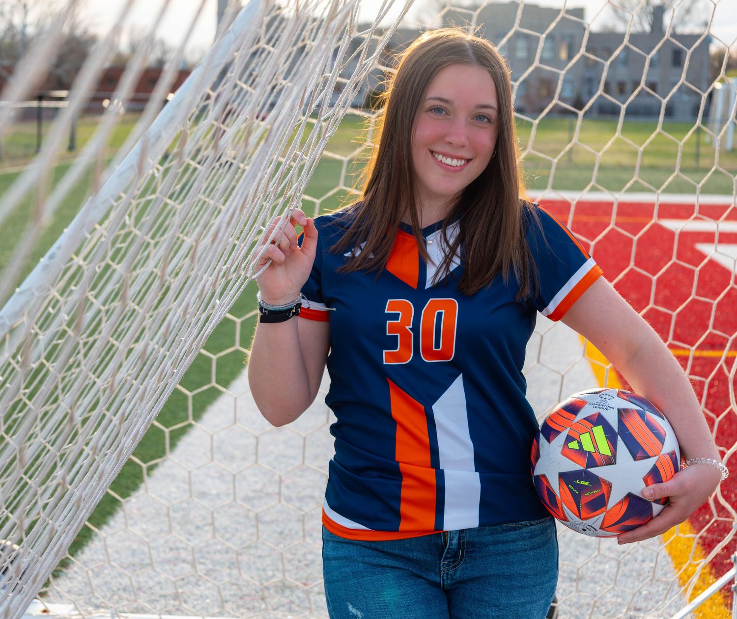 This homeschool senior holding a soccer ball during her session at Evangel In Springfield MO with Refined by Fire Photography.