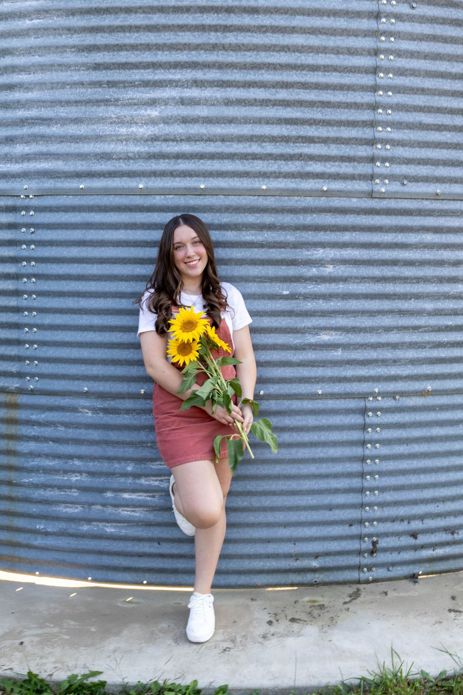 This girl is holding her favorite flowers, Sunflower posing for her senior photos in Marshfield Missouri with Refined by Fire Photography.