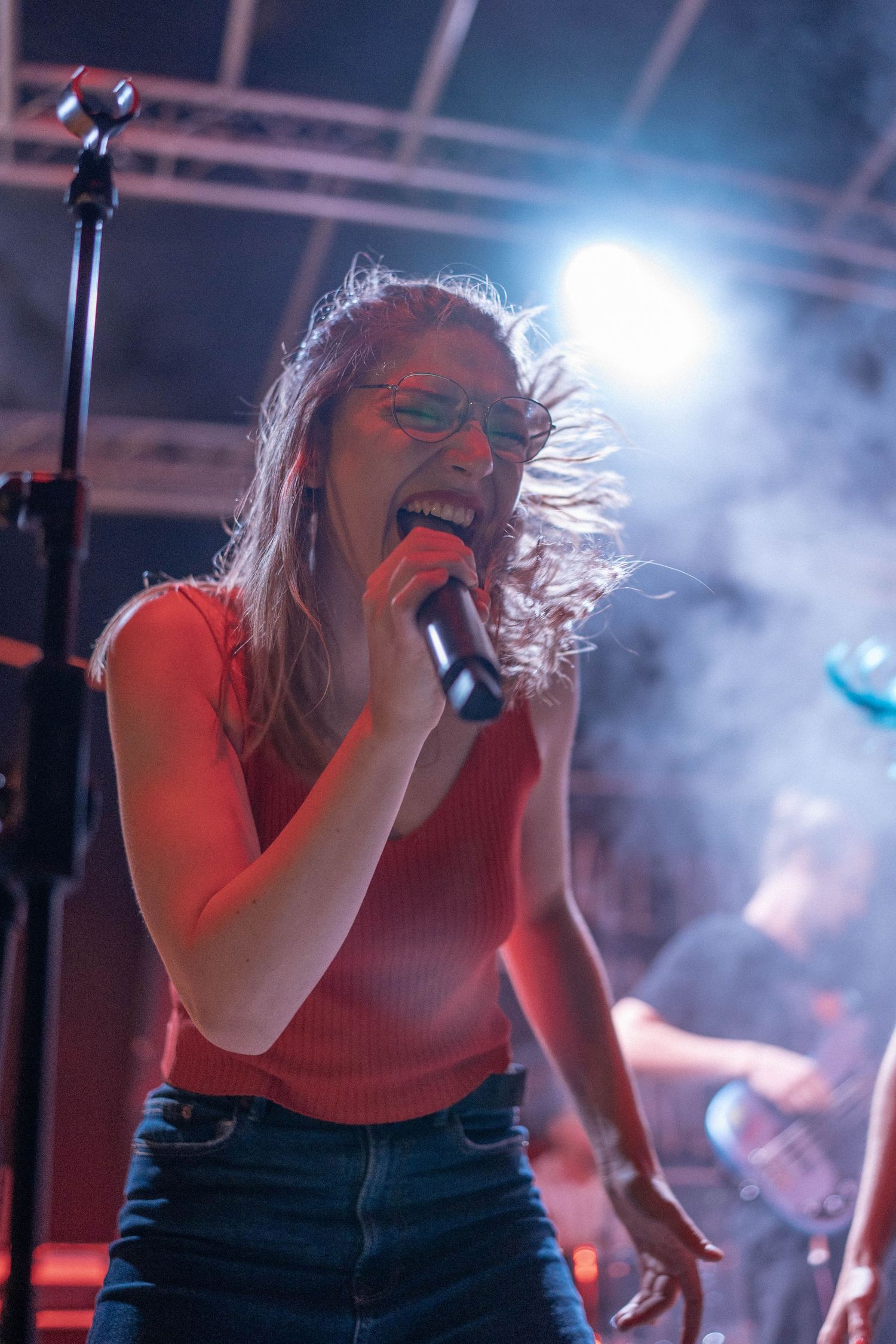 Concert performer singing passionately into microphone under dramatic stage lighting.