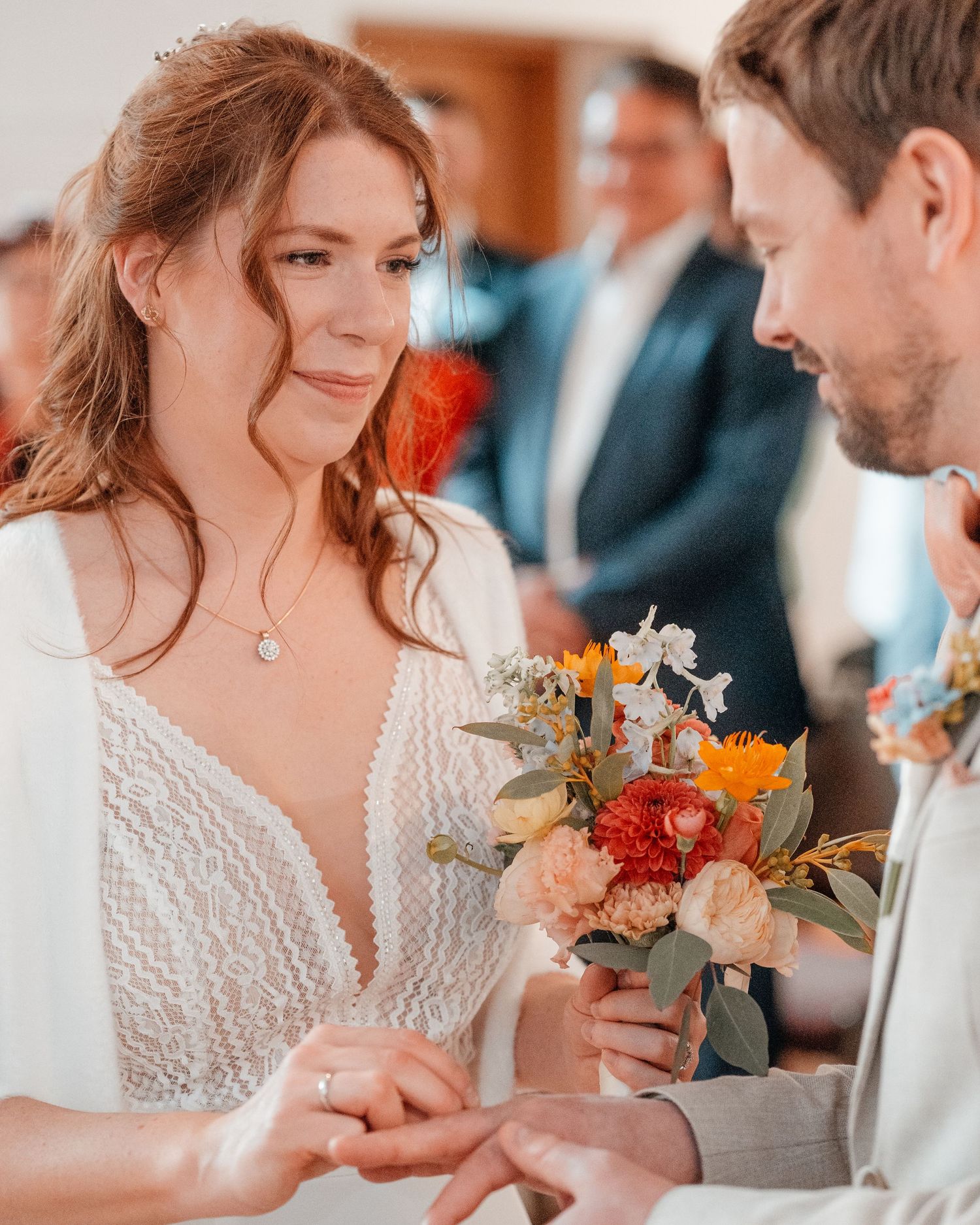 Bride and groom share an intimate moment during their wedding ceremony while holding colorful autumn bouquet.