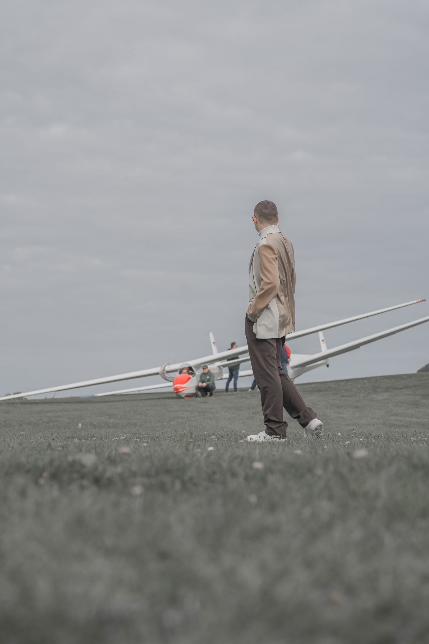 Person walking near a small aircraft on a cloudy day.