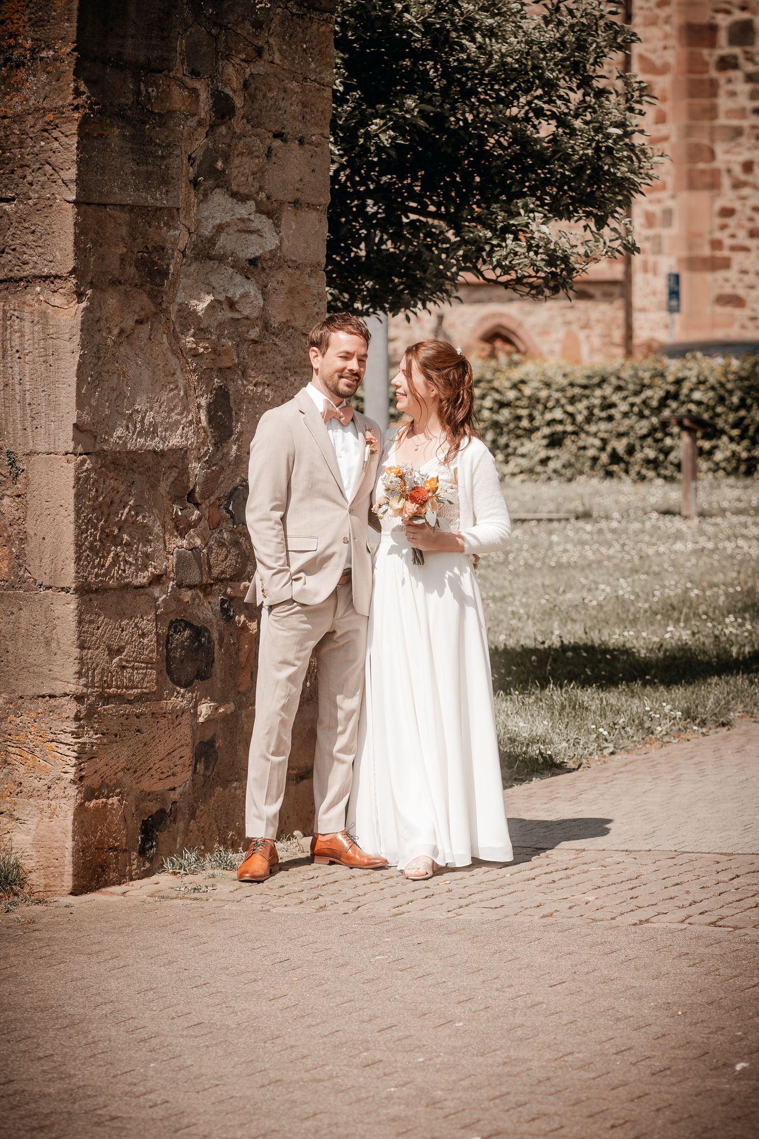 A couple shares a joyful moment together against a rustic brick wall backdrop during a wedding photo session.