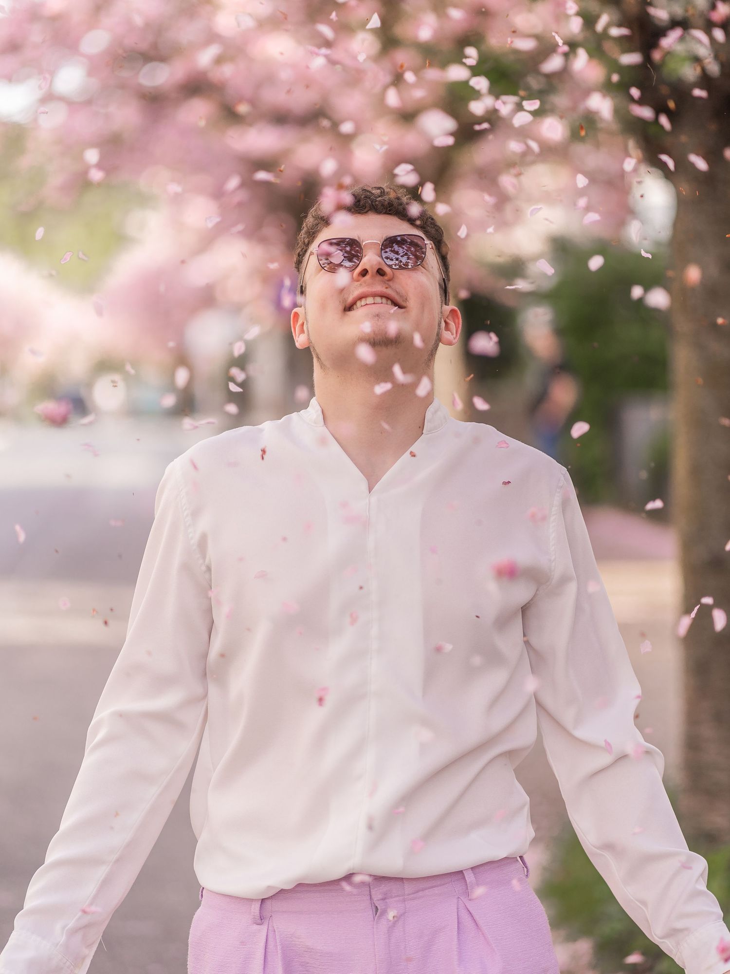 Spring portrait with cherry blossoms falling in soft pink lighting.