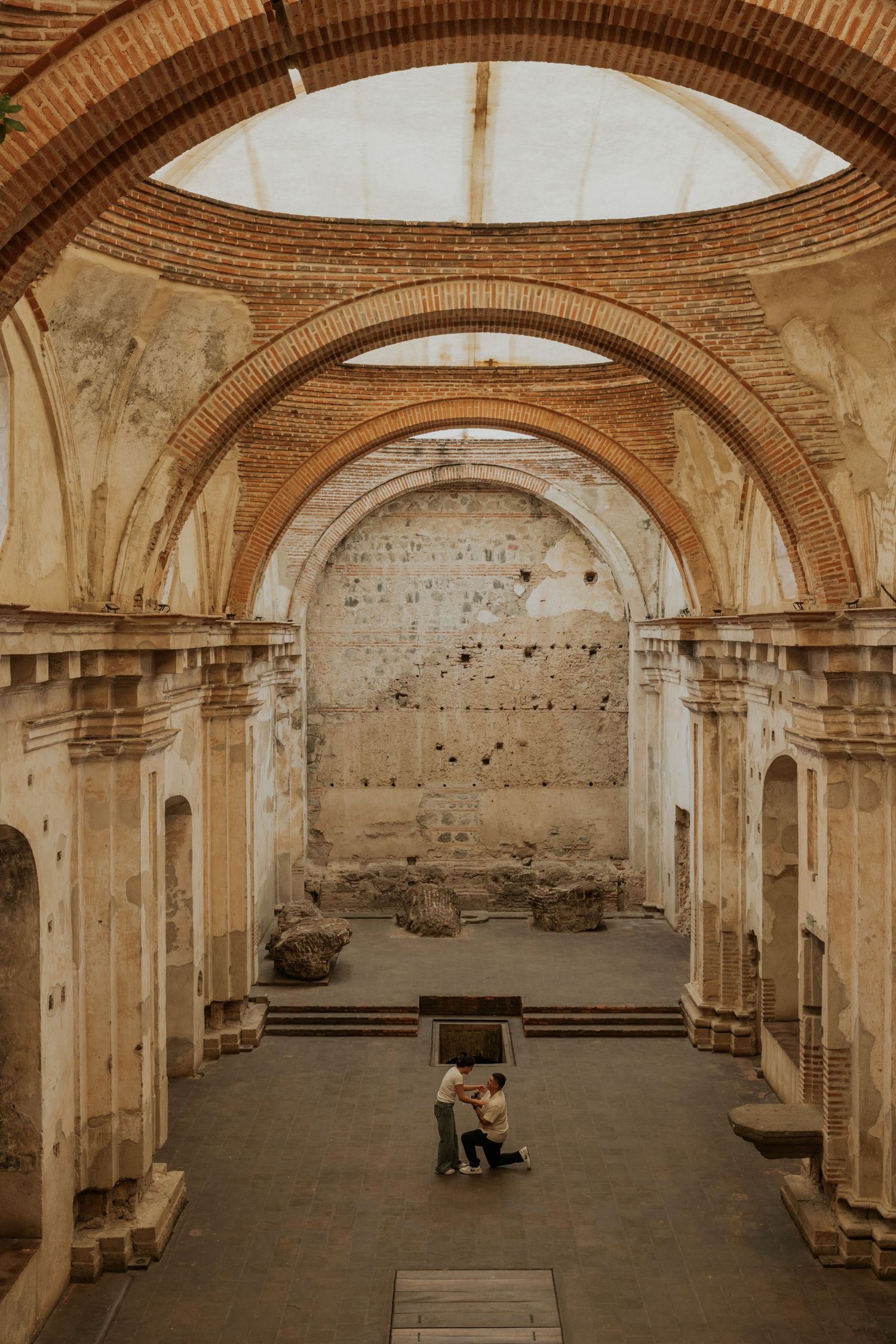 Couple embracing inside ancient ruined church with brick arched ceilings and weathered stone walls in Antigua, Guatemala.