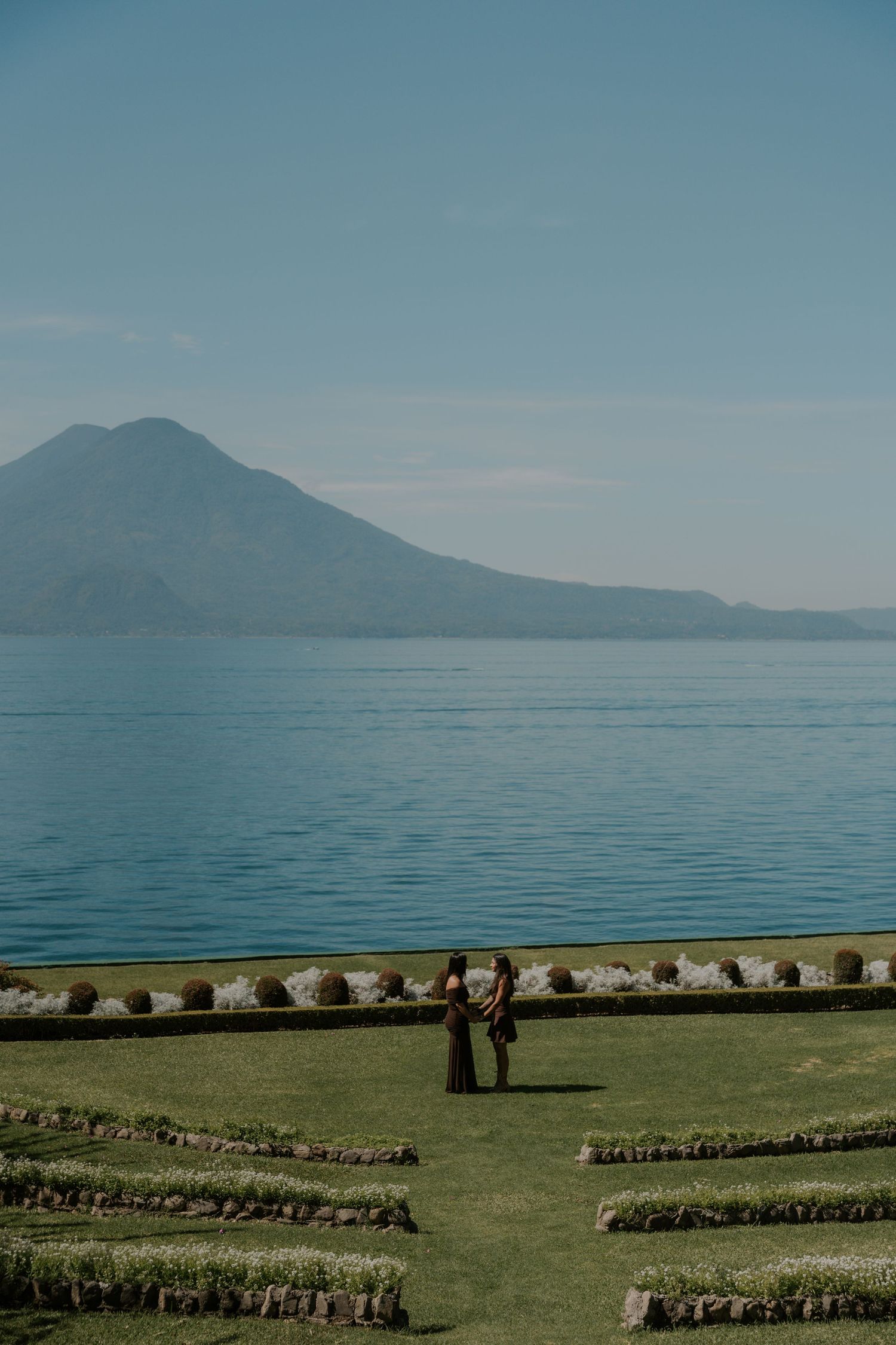 Panoramic view of Lake Atitlan in Guatemala with green pastures and volcanic mountains in the background.