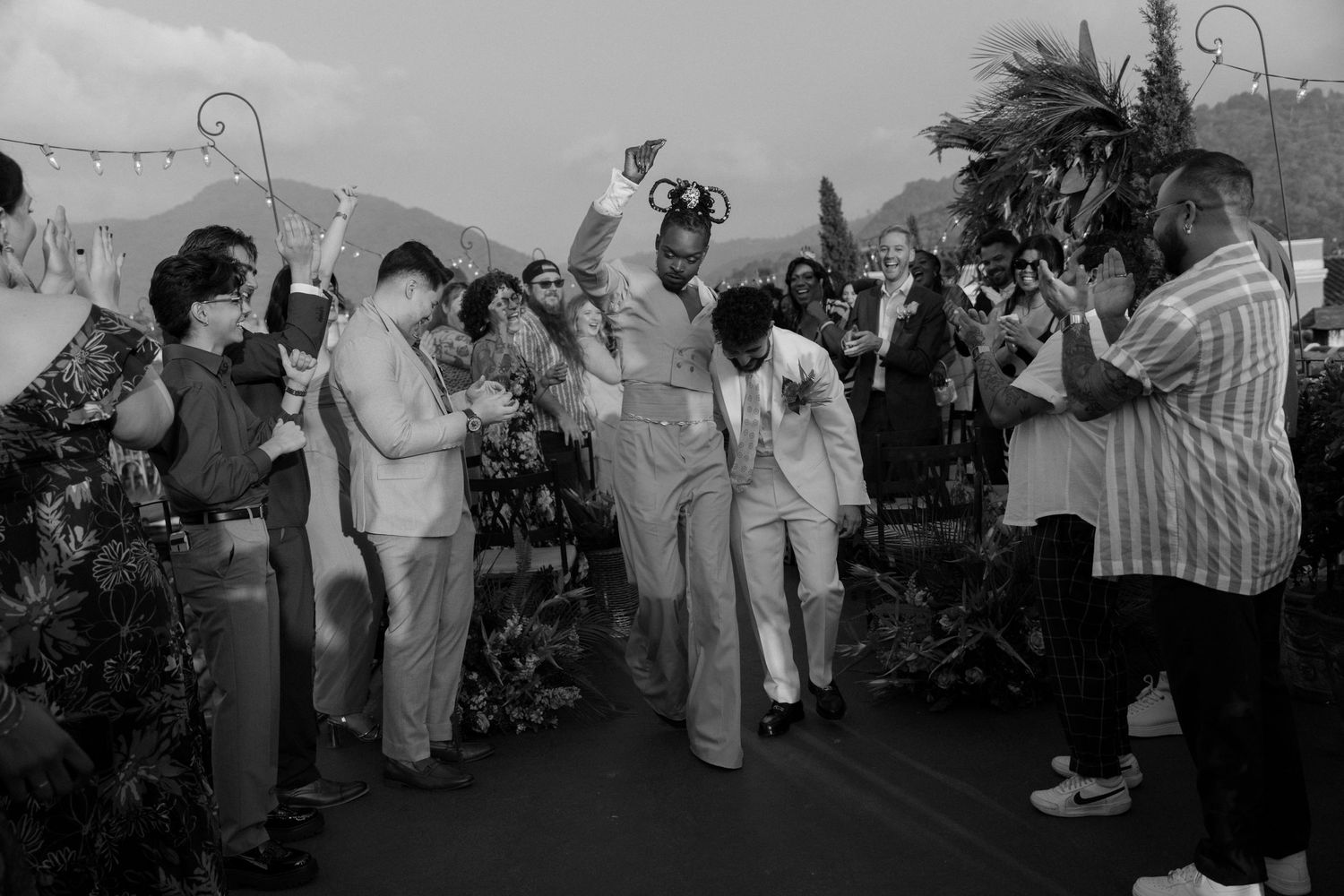 Black and white celebration photograph of dancing guests at an outdoor event.