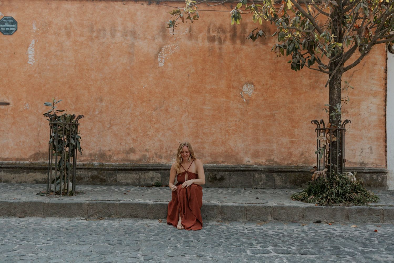 Girl standing against weathered orange wall with climbing vines in an old European courtyard.