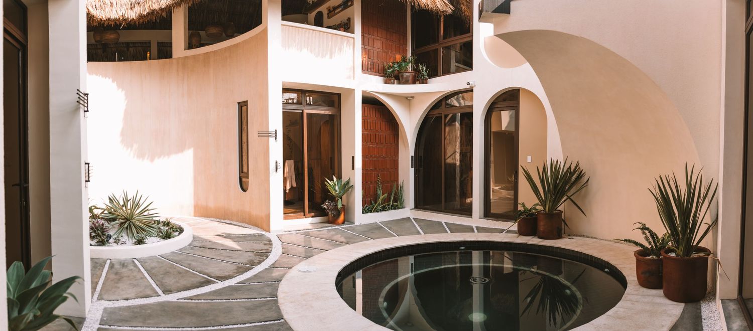Modern interior courtyard with curved white walls and circular reflecting pool.