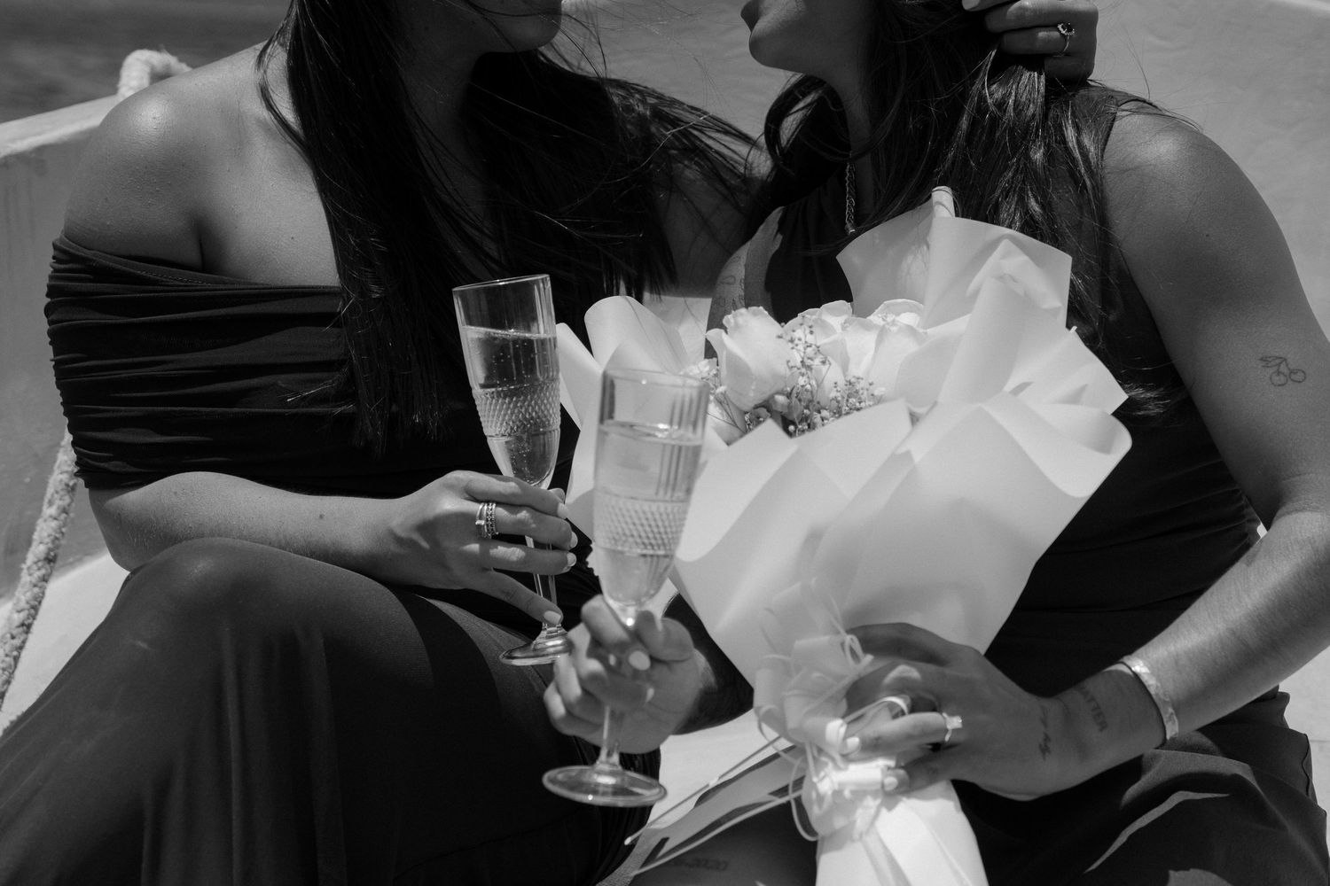 Black and white photo of champagne glasses and formal attire at an elegant celebration event.