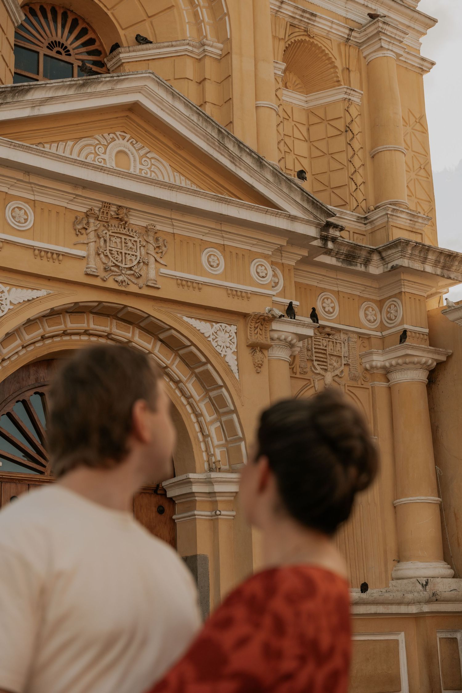 Ornate yellow colonial church facade with decorative arches and architectural details in warm evening light.