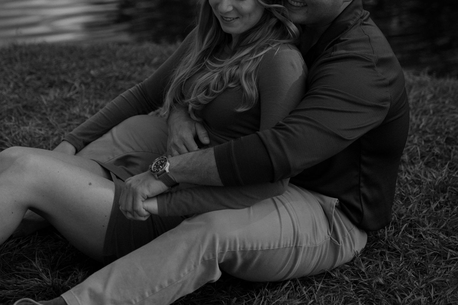 An intimate black and white photo of a couple relaxing in the grass.