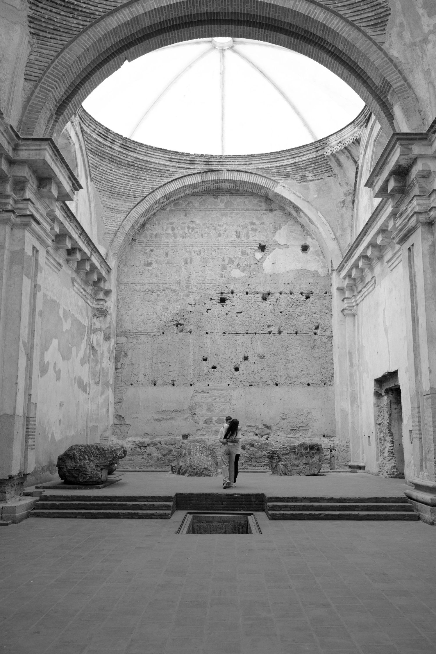 Black and white photo of ancient ruined church interior with arched ceiling, weathered stone walls, and lone visitor.