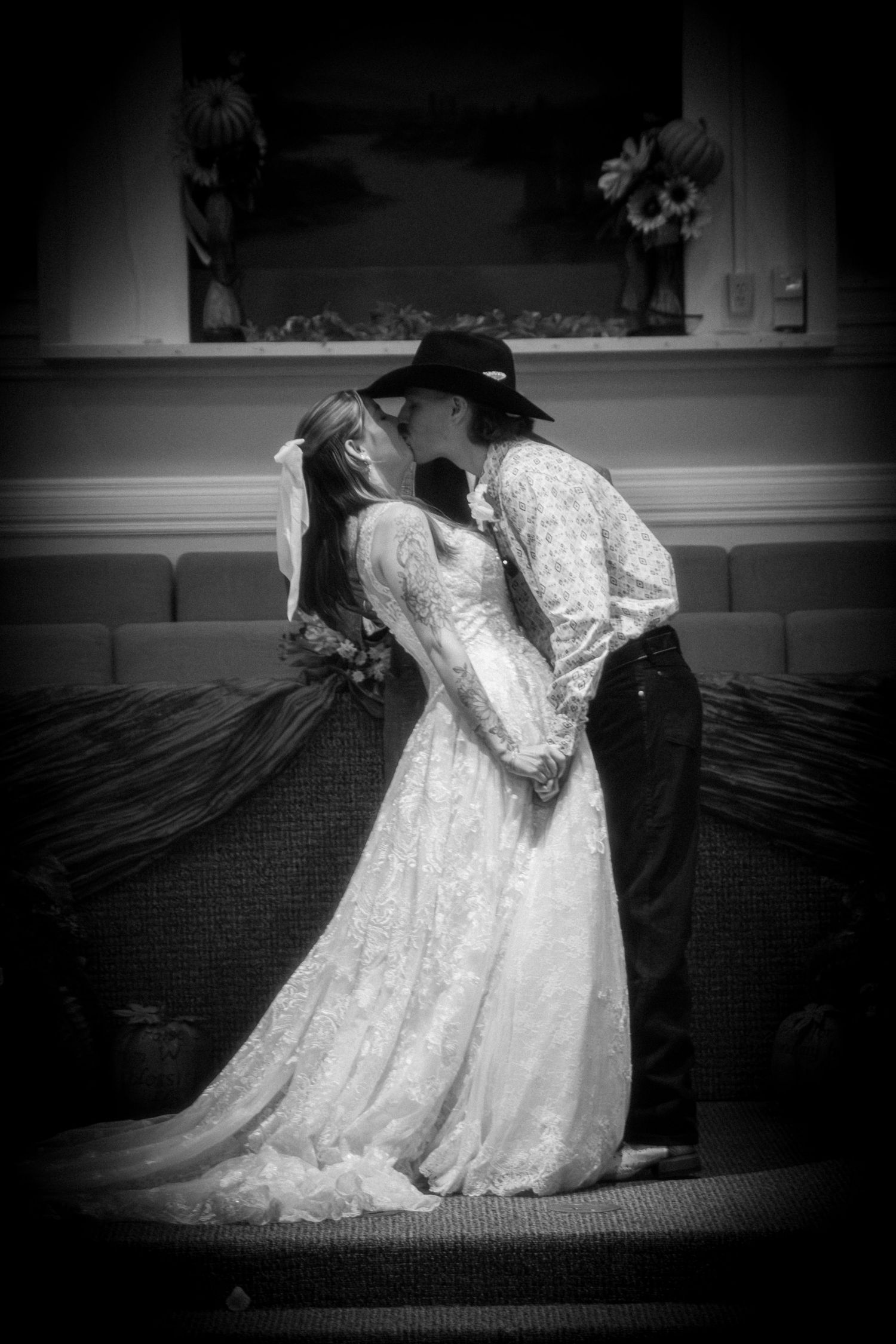 Black and white photo of bride and groom sharing first kiss at wedding altar.