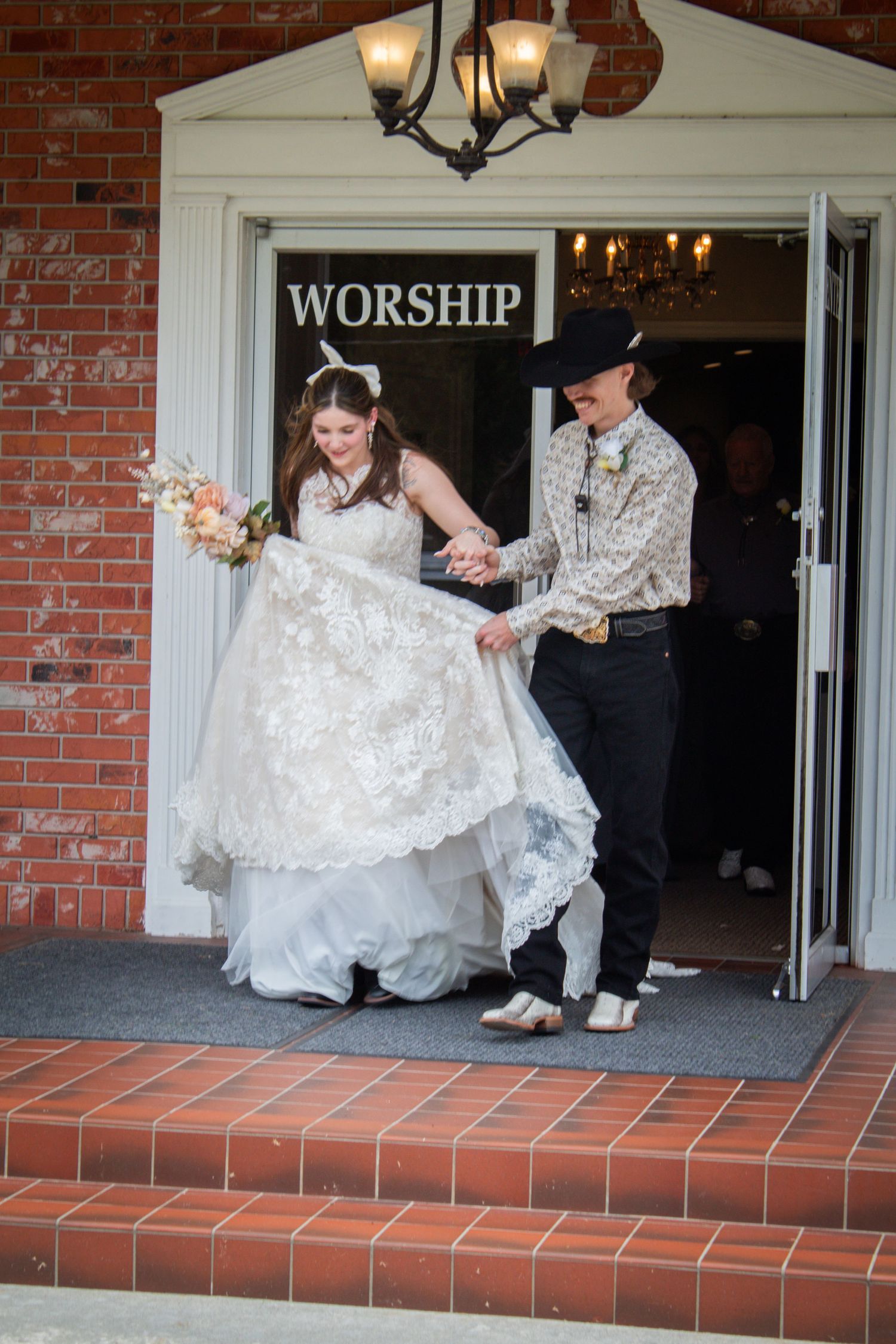 Newlywed couple exiting church under Worship sign after wedding ceremony.