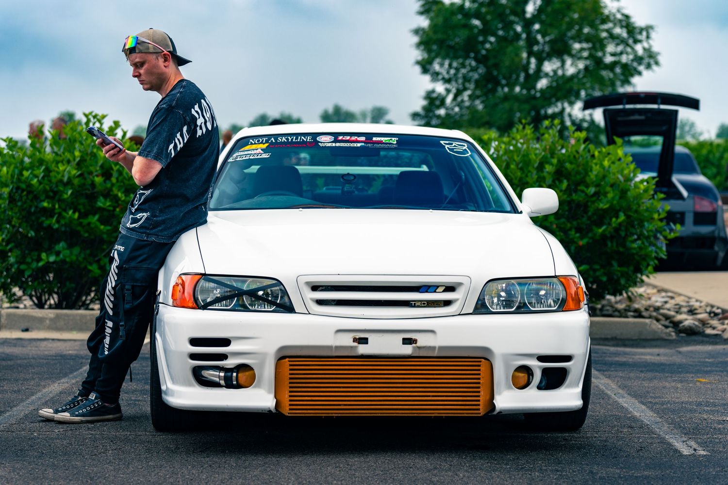 A car enthusiast leans on his car at a show