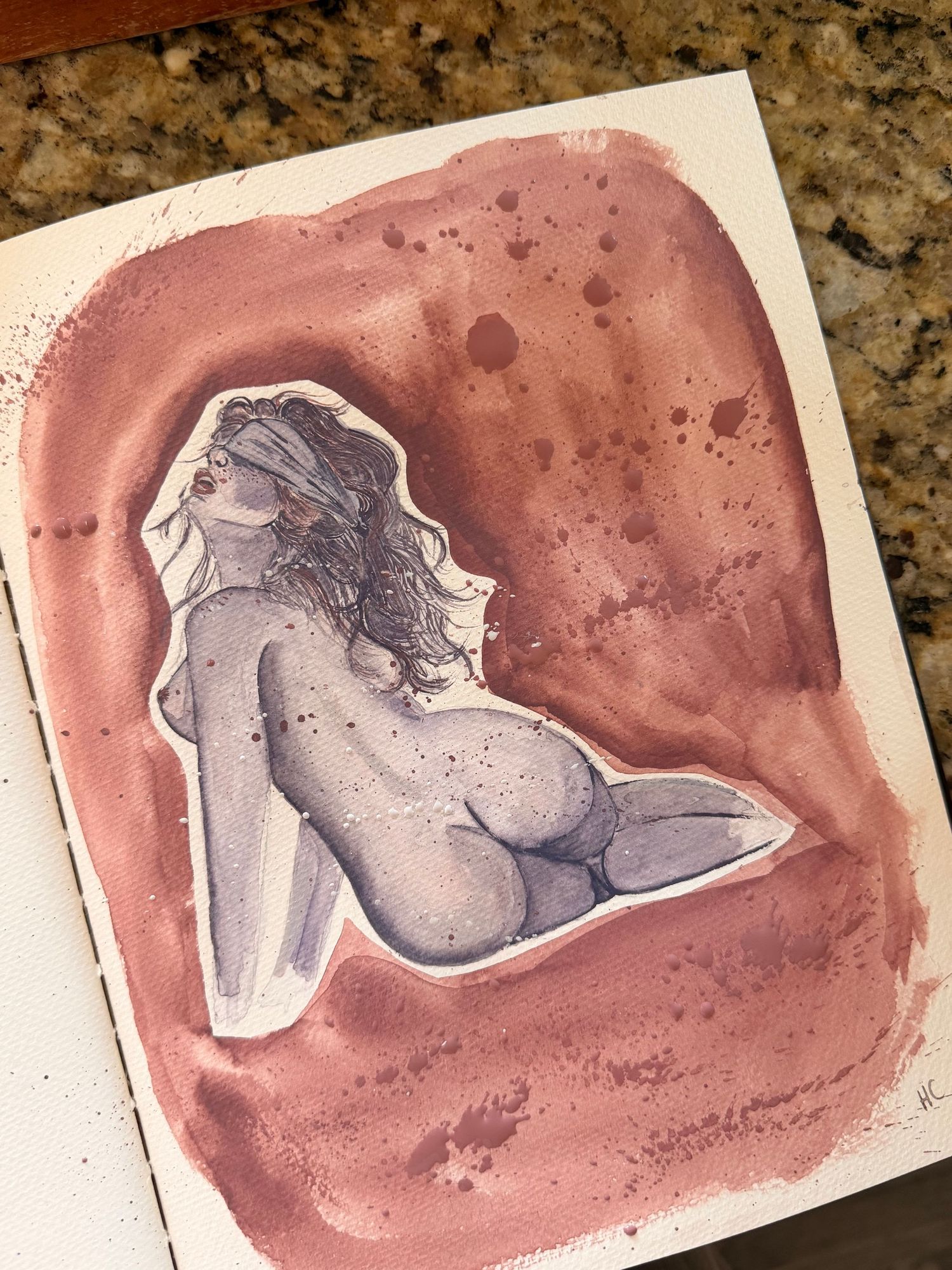 Watercolor painting of a nude figure with a blindfold reclining on a textured reddish-brown splattered background in an open sketchbook.