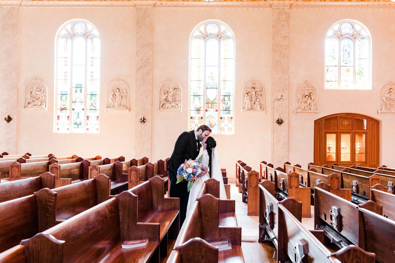 Panoramic view of a church interior with arched windows and wooden pews.