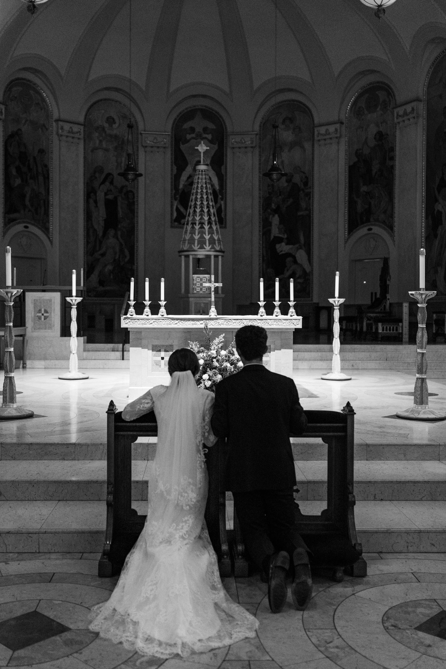 Black and white church interior with wedding ceremony silhouettes and candles.